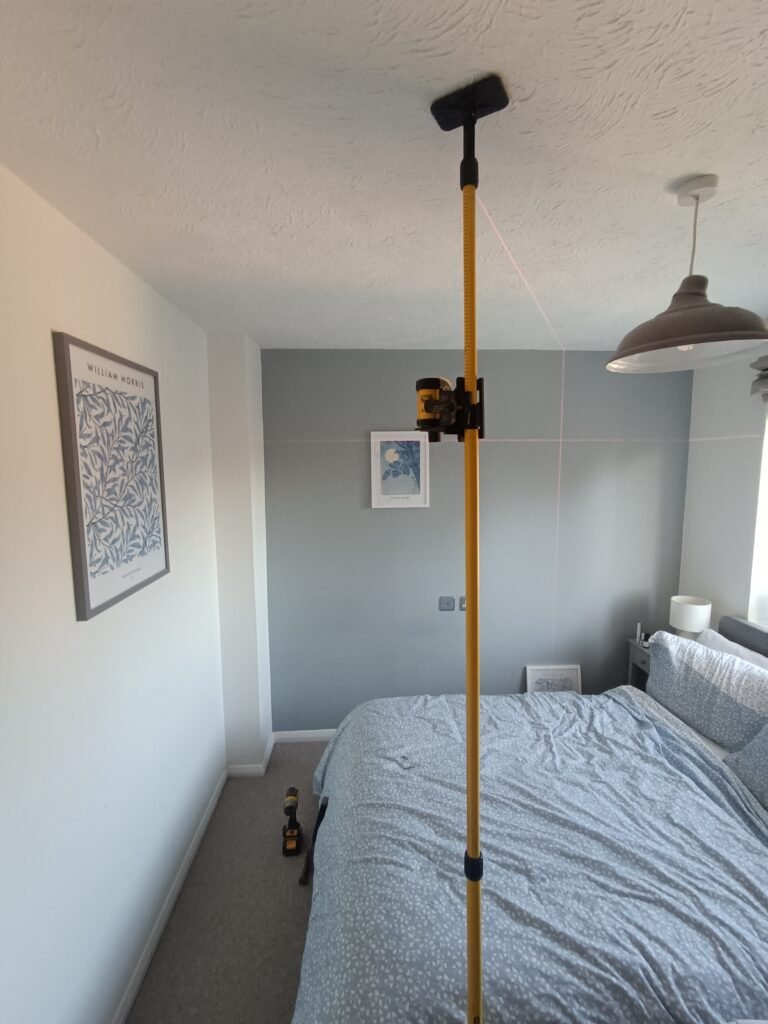 Using a laser level to hang pictures straight on a bedroom wall