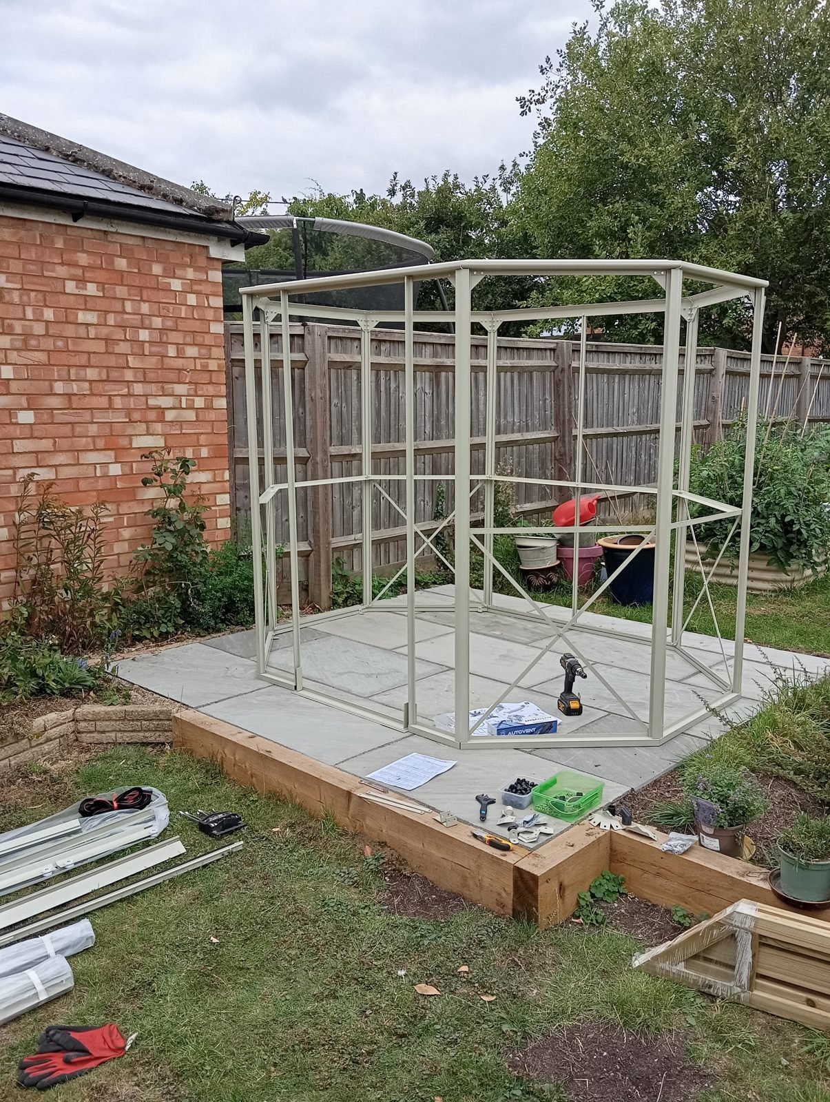 Aluminium greenhouse wall frame with cross bracing on a paved base