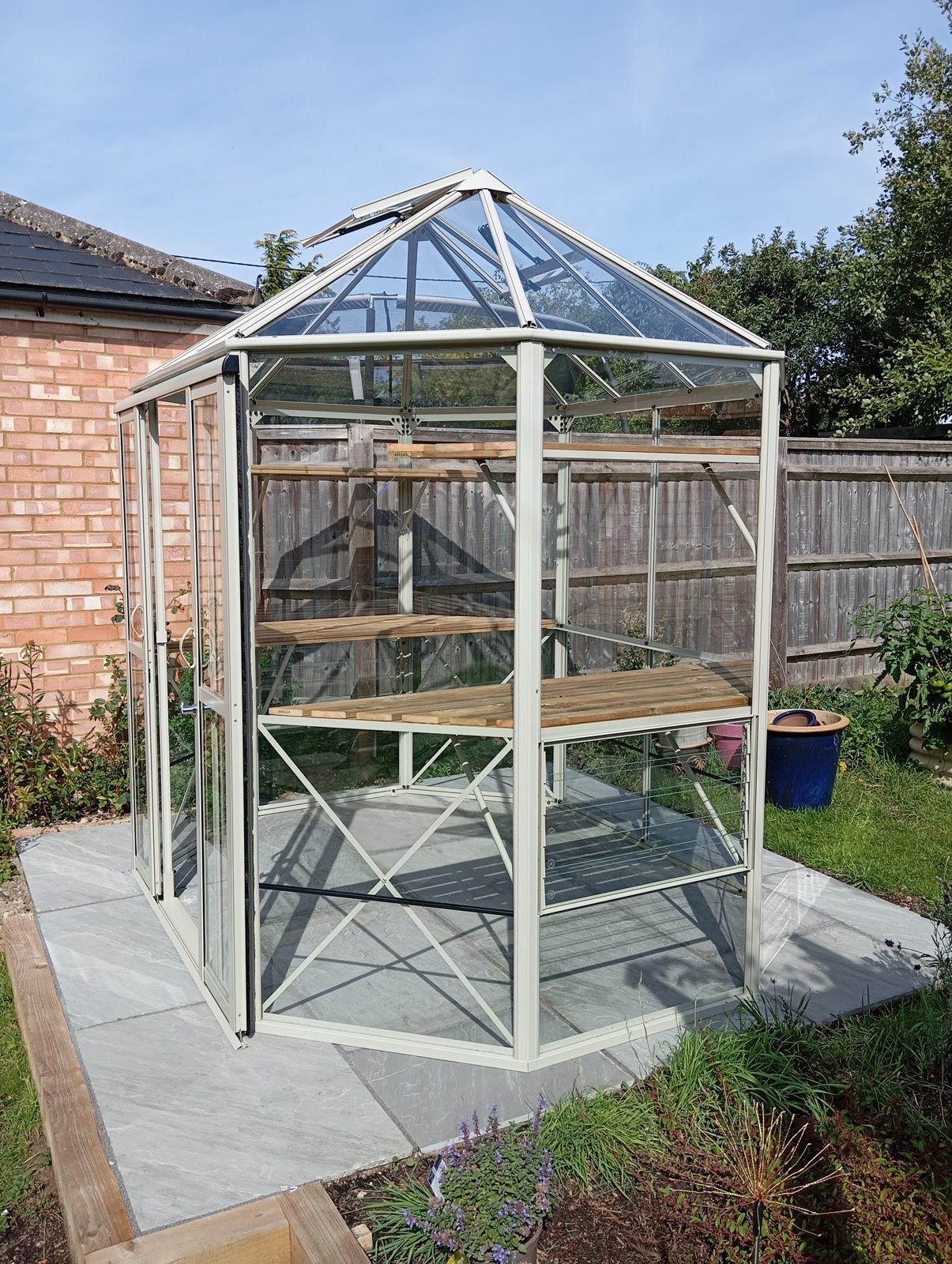 Inside view of finished greenhouse showing slatted wooden staging and louvre vent