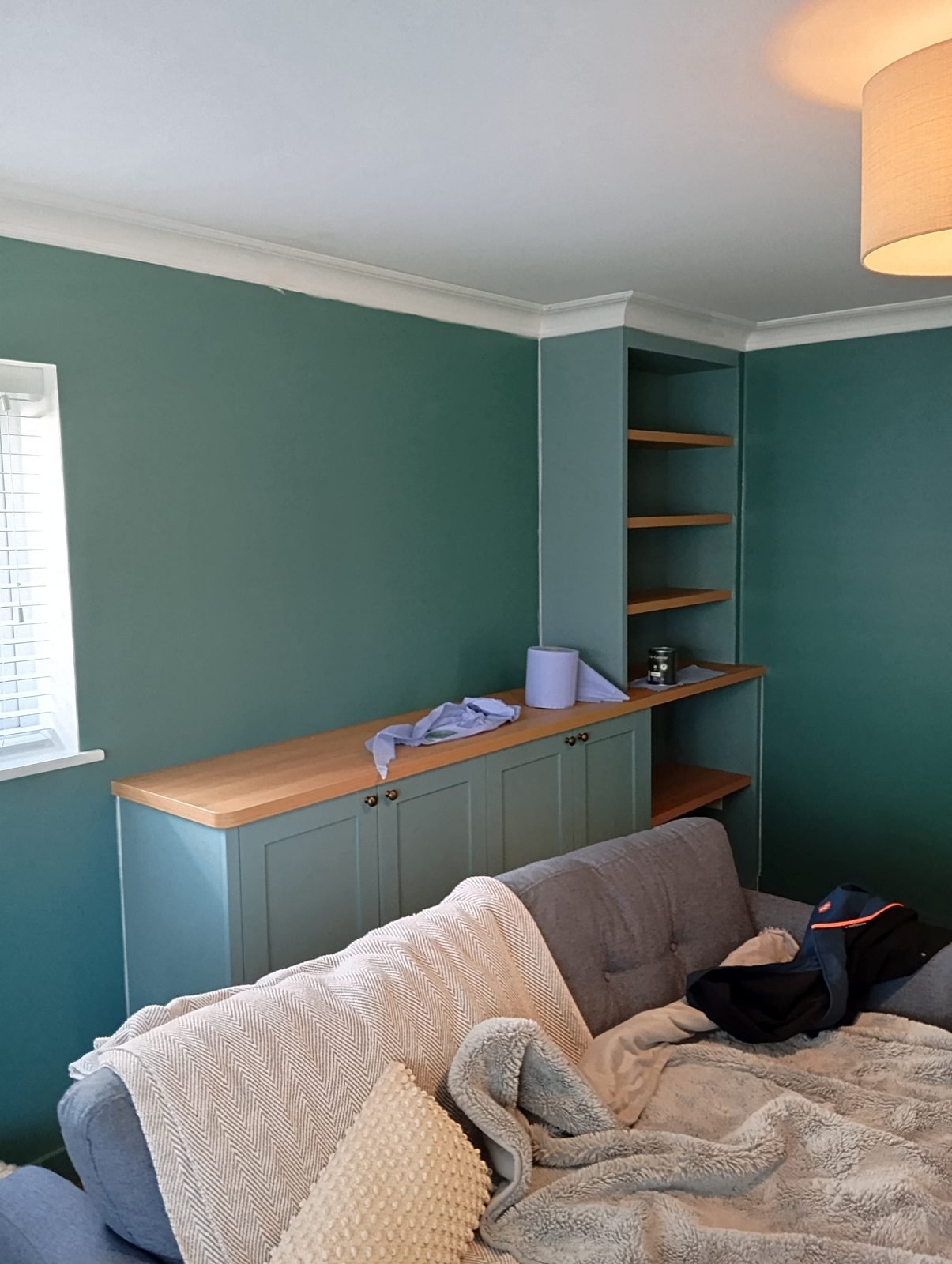 Painted sage green alcove cupboards and shelves with oak tops in a green living room