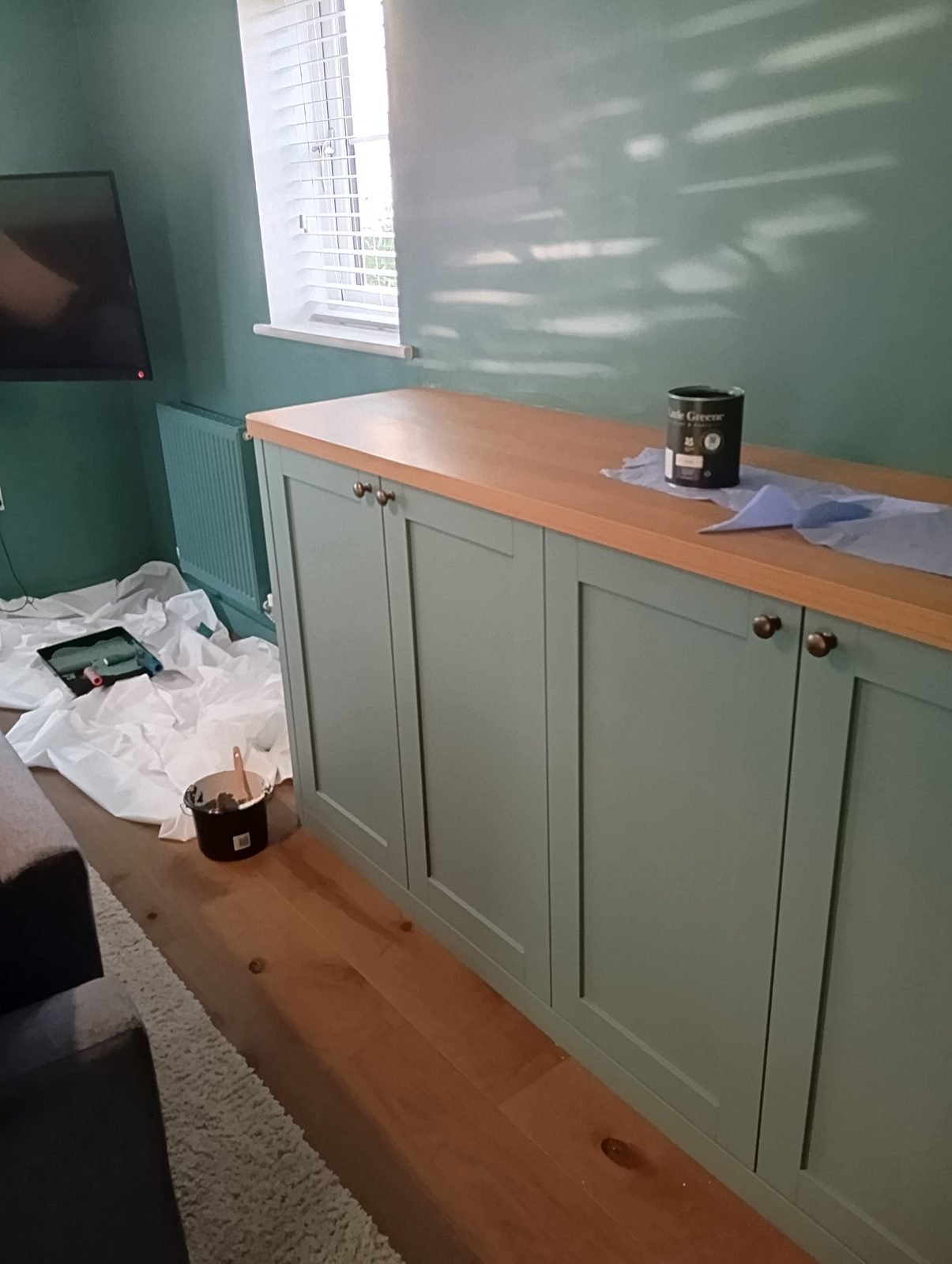 Close-up of painted sage green shaker cupboard doors with oak top