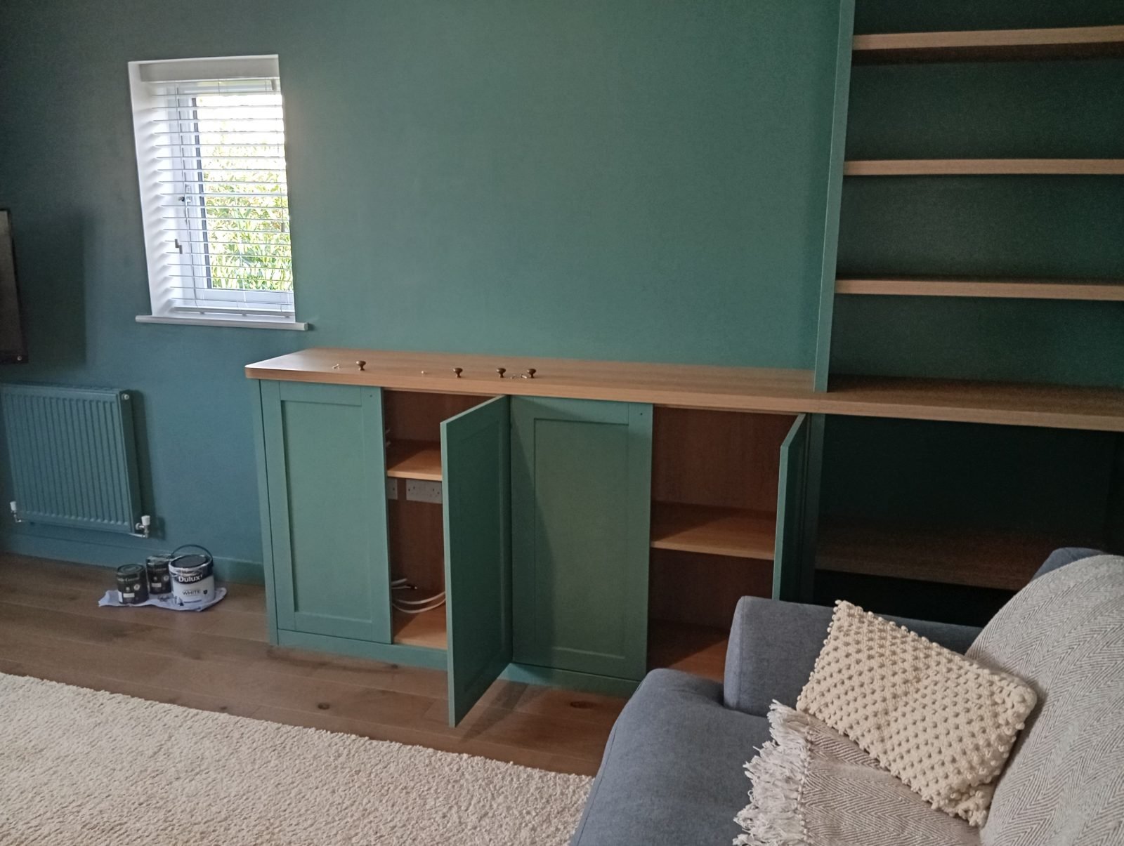 Finished living room with deep green walls and sage green alcove units